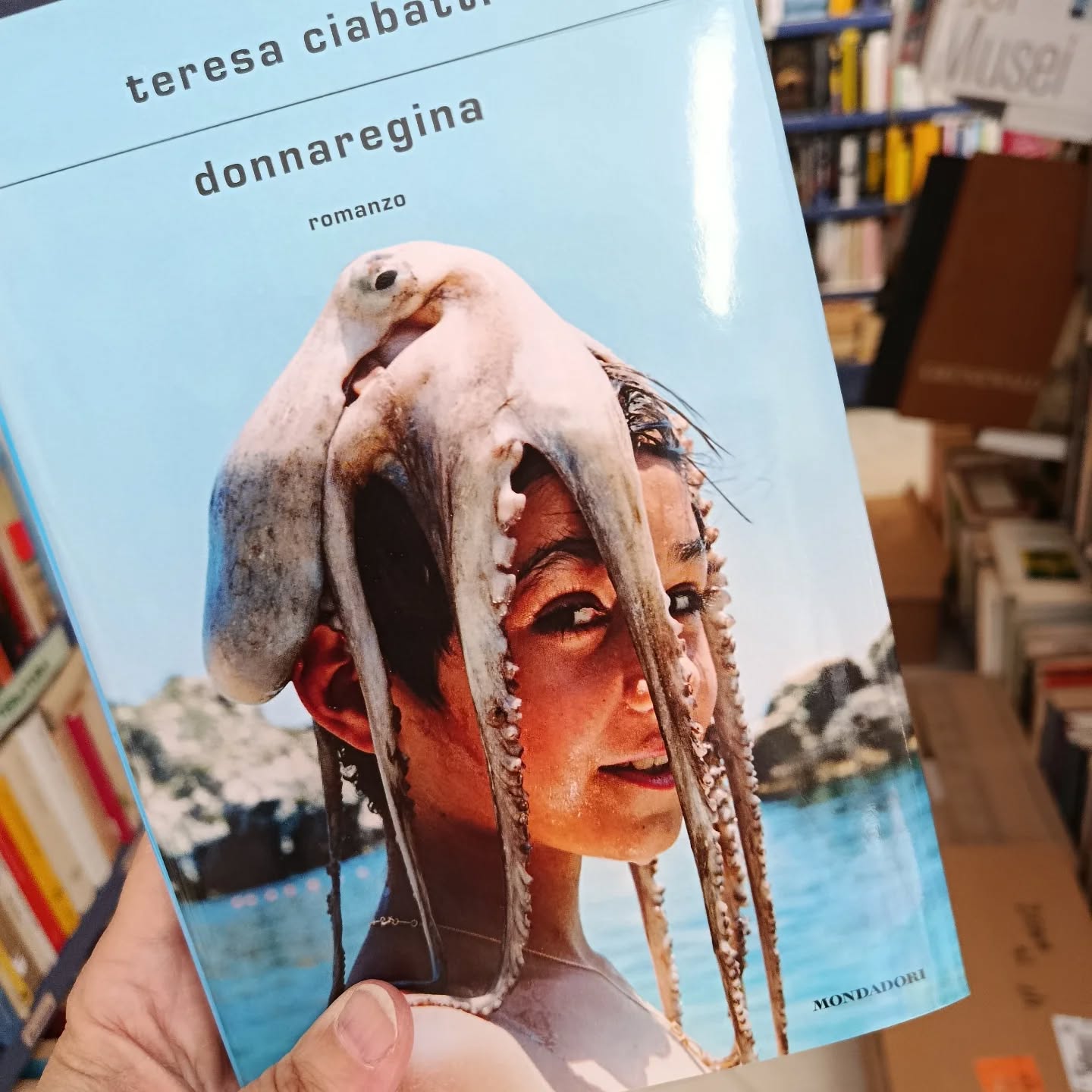 "Donna regina"
di Teresa Ciabatti
Mondadori editore 

Finalista Premio Strega 2026

Chi è davvero 'o Nasone, accusato di rapina a mano armata, associazione a delinquere, associazione mafiosa, 182 omicidi commessi e commissionati? Se lo chiede la scrittrice a cui il giornale dà l'incarico di intervistare proprio lui, il superboss. A lei che di criminalità non sa niente, che si è sempre occupata di adolescenti, tutt'al più cantanti, attrici, gente dello spettacolo. Il loro è l'incontro di due mondi lontanissimi che tali devono rimanere, almeno nelle intenzioni della protagonista.
Eppure, quando lui inizia a parlare, qualcosa cambia. Quest'uomo spietato che alleva colombi e crede negli ufo comincia a interessarla. Non tanto quando si sofferma sulle cronache di furti, sparatorie e vendette, piuttosto per la nostalgia che vibra nei racconti delle donne incontrate e perdute, degli amici morti ammazzati, degli affetti famigliari. Quando insomma, pur non rinnegando il proprio passato, il boss si mostra vulnerabile. Il dubbio: forse la sta manipolando? È sul piano dei rapporti affettivi che i due si incontrano: nelle ferite di genitori incerti, forse sbagliati. Nel mistero dei figli con cui non sanno più comunicare e che temono di aver perso per sempre. Il confronto tra loro, pur sempre carico di diffidenza, si trasforma allora in un viaggio tra ricordi, confessioni, fraintendimenti e proiezioni, ma soprattutto rivelazioni su figli che non sono quello che loro credono. Così, quando la protagonista si trova a cercare le tracce del figlio del boss nelle strade di Napoli, capisce di cercare qualcun altro: sua figlia che le sta sfuggendo.

#teresaciabatti #donnaregina #mondadorieditore #finalistapremiostrega2026